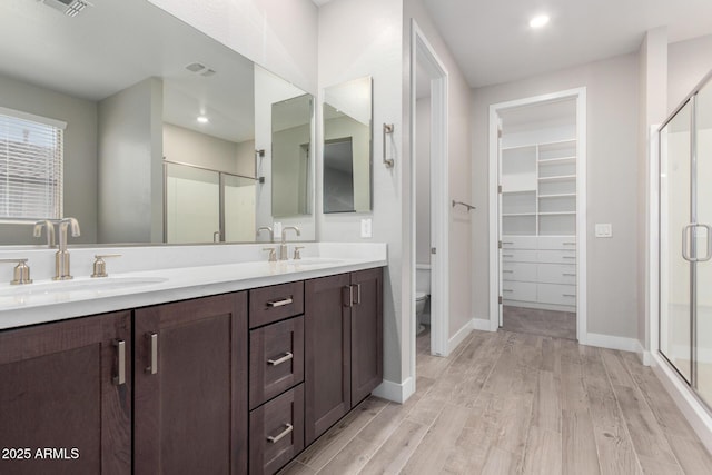 bathroom featuring hardwood / wood-style flooring, vanity, toilet, and a shower with door