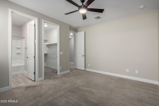 unfurnished bedroom with a walk in closet, light colored carpet, connected bathroom, and a closet