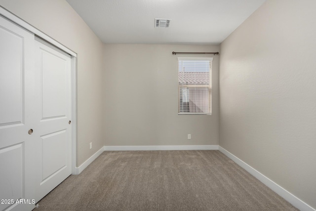 unfurnished bedroom with light colored carpet and a closet