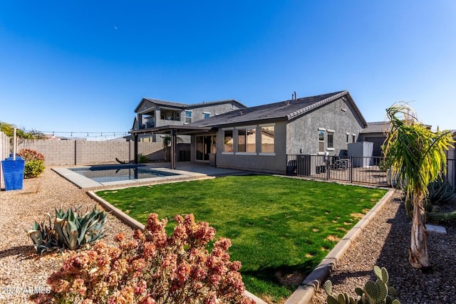 back of house with a fenced in pool, a lawn, and a patio