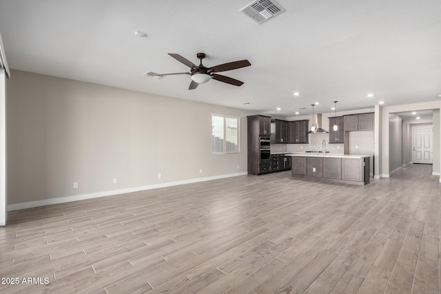 unfurnished living room with ceiling fan, sink, and light hardwood / wood-style floors