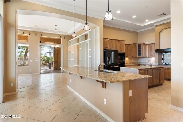 kitchen featuring black appliances, a spacious island, hanging light fixtures, light tile patterned floors, and a kitchen bar