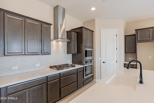 kitchen featuring dark brown cabinetry, sink, wall chimney exhaust hood, tasteful backsplash, and appliances with stainless steel finishes