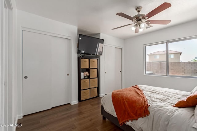 bedroom featuring dark wood-type flooring, two closets, and ceiling fan