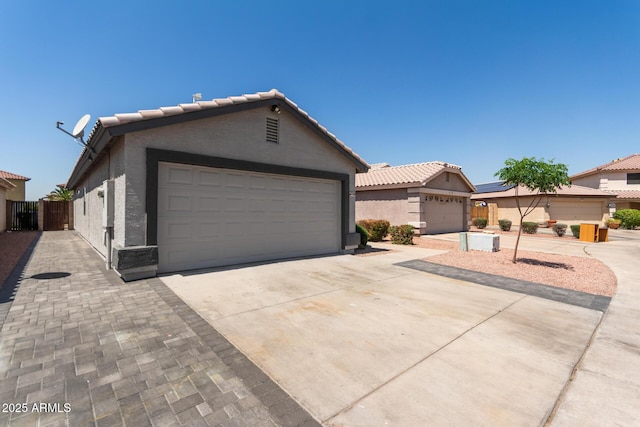 ranch-style house with a tiled roof, driveway, stucco siding, and fence