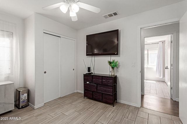 bedroom with wood finish floors, a closet, a ceiling fan, visible vents, and baseboards