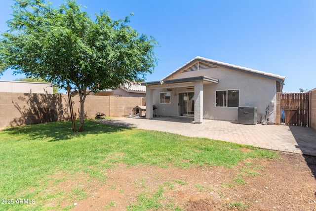 back of house featuring a lawn, a fenced backyard, a patio area, and central AC