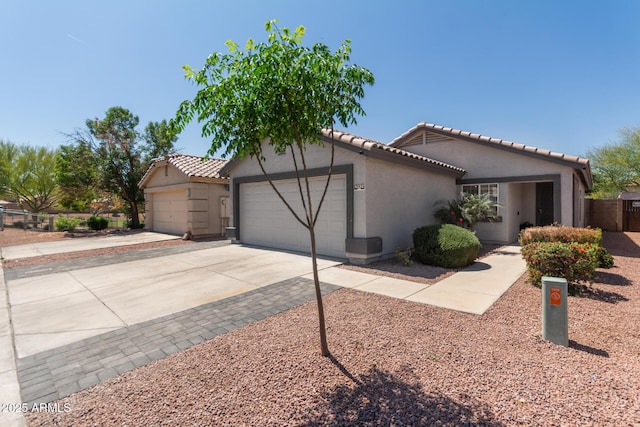 ranch-style home with a tiled roof, an attached garage, driveway, and stucco siding