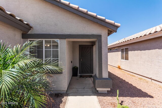 property entrance featuring a tile roof and stucco siding