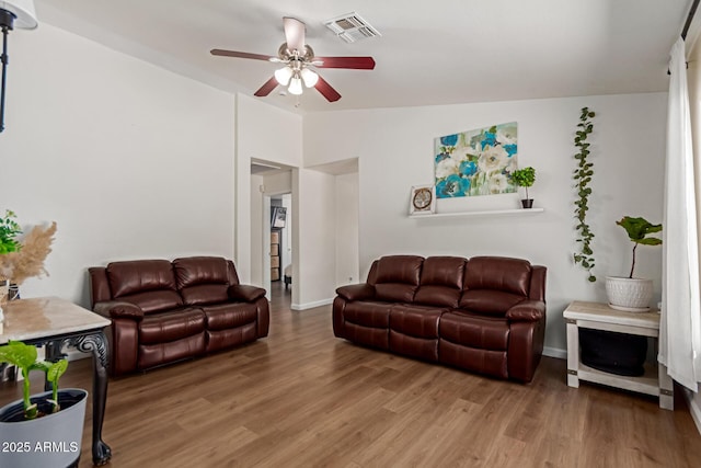living area with lofted ceiling, light wood-type flooring, baseboards, visible vents, and ceiling fan