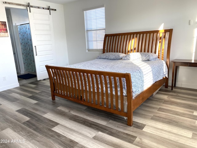 bedroom with wood-type flooring and a barn door