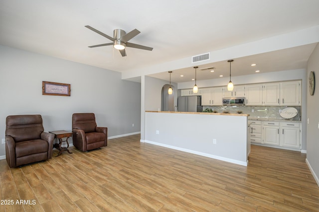 living area featuring baseboards, ceiling fan, visible vents, and light wood-style flooring
