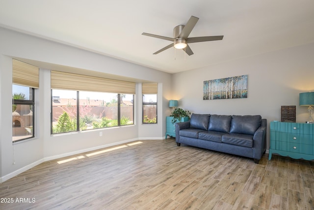 living area with baseboards, ceiling fan, and wood finished floors