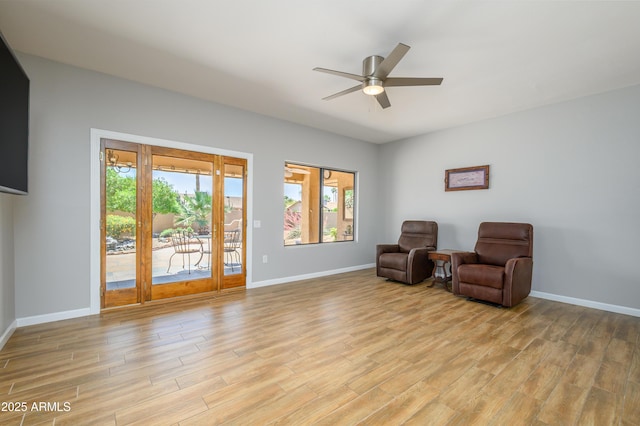 sitting room with light wood-type flooring, baseboards, and a healthy amount of sunlight