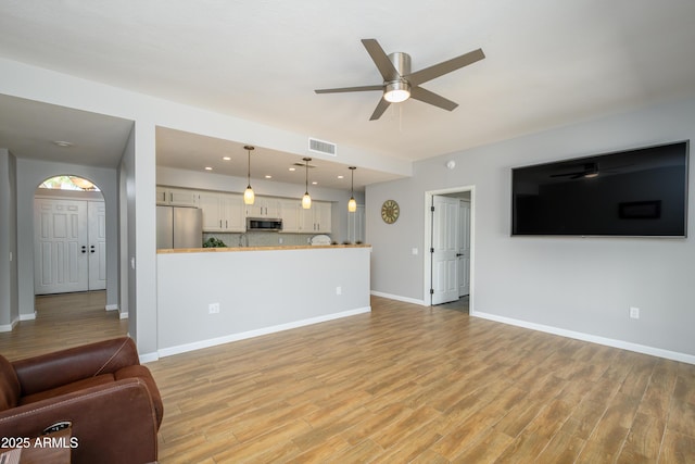 unfurnished living room with baseboards, a ceiling fan, light wood-type flooring, and visible vents