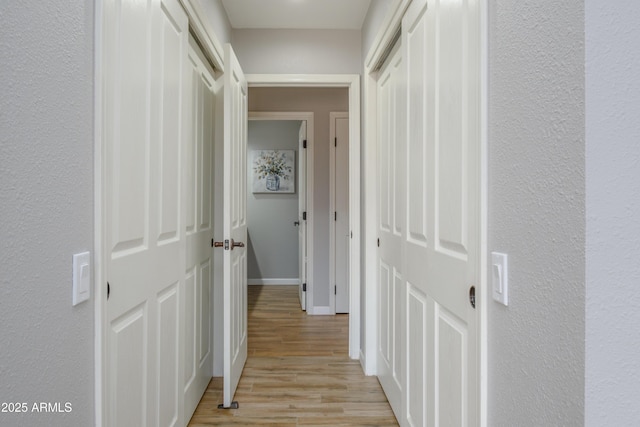 corridor featuring baseboards and light wood-style floors