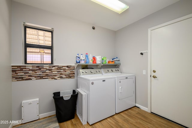 laundry area featuring baseboards, laundry area, washer and clothes dryer, and light wood-style flooring