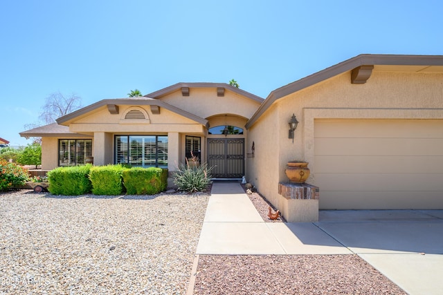 property entrance with a garage, stucco siding, and driveway