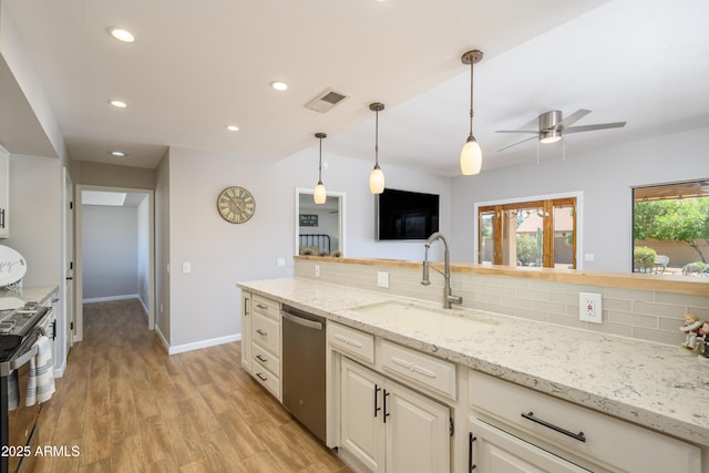kitchen with a sink, appliances with stainless steel finishes, a ceiling fan, and backsplash