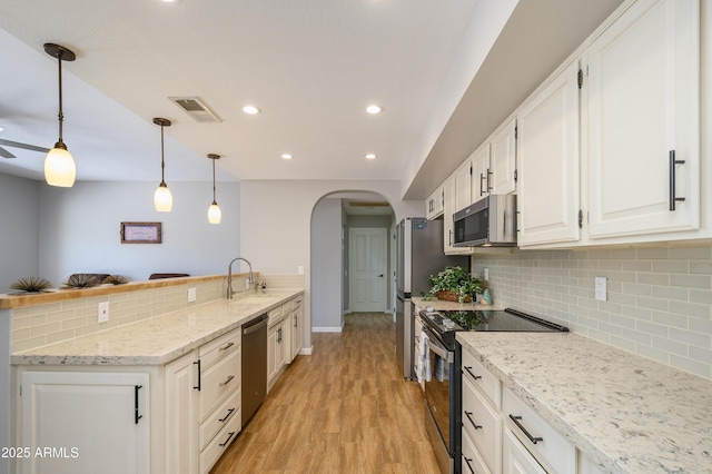 kitchen featuring visible vents, arched walkways, tasteful backsplash, a sink, and stainless steel appliances