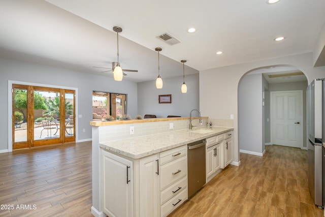 kitchen with visible vents, arched walkways, a sink, a peninsula, and stainless steel appliances
