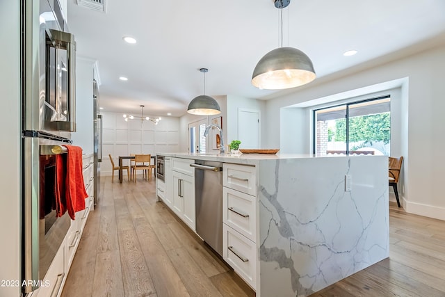 kitchen featuring stainless steel appliances, hanging light fixtures, and a kitchen island with sink