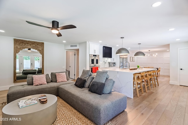 living room with ceiling fan, sink, french doors, and light wood-type flooring