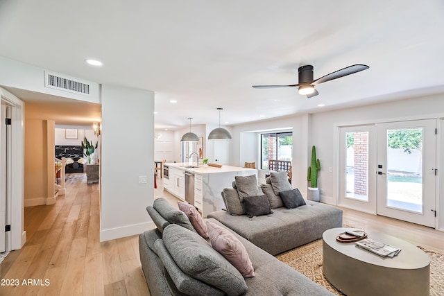 living room with ceiling fan, light wood-type flooring, and sink