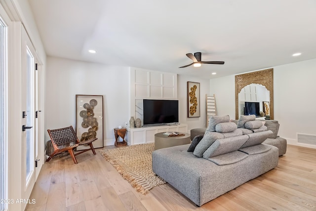 living room featuring light hardwood / wood-style flooring and ceiling fan