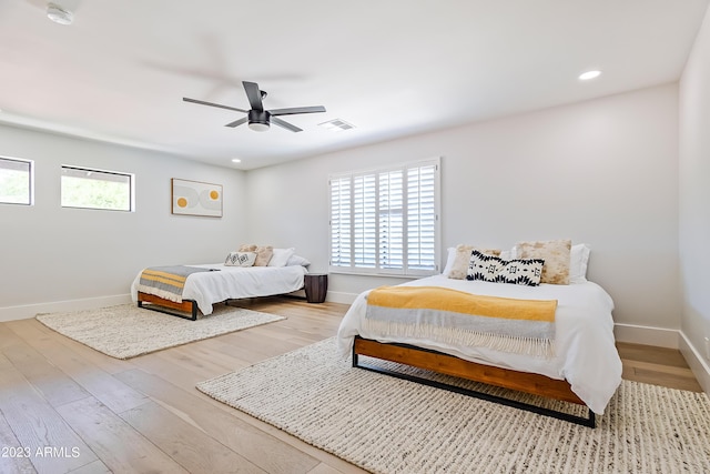 bedroom with ceiling fan, light hardwood / wood-style floors, and multiple windows