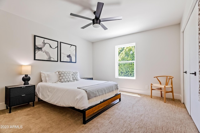 bedroom with ceiling fan, light colored carpet, and a closet