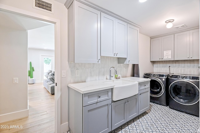 laundry area with cabinets, separate washer and dryer, and sink