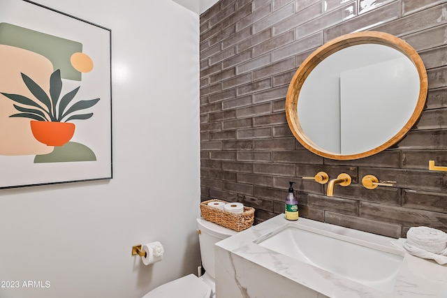 bathroom featuring decorative backsplash, sink, and toilet