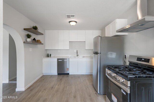 4207 W Culver St, Phoenix, AZ 85009 - kitchen featuring stainless steel appliances, wall chimney exhaust hood, open shelves, white cabinetry, and light wood-style flooring