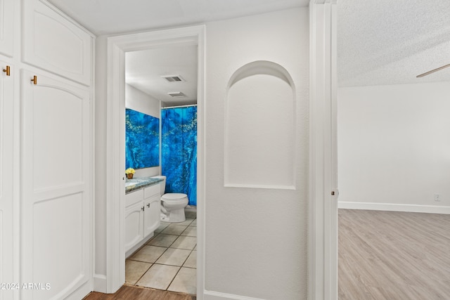 bathroom with vanity, toilet, a textured ceiling, and hardwood / wood-style flooring