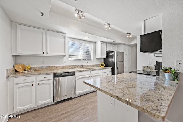 kitchen featuring kitchen peninsula, light stone countertops, stainless steel appliances, and white cabinets