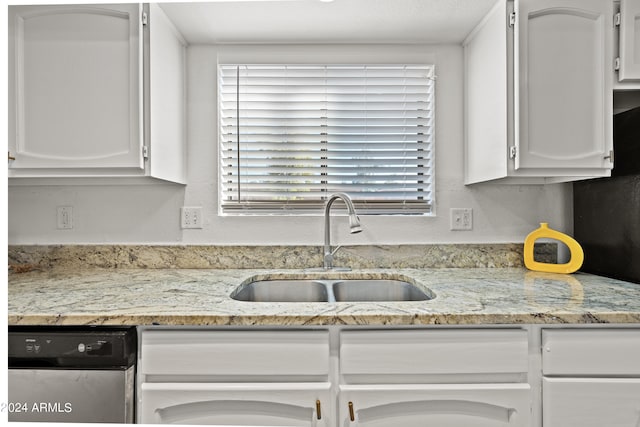 kitchen featuring stainless steel dishwasher, light stone countertops, sink, and white cabinetry