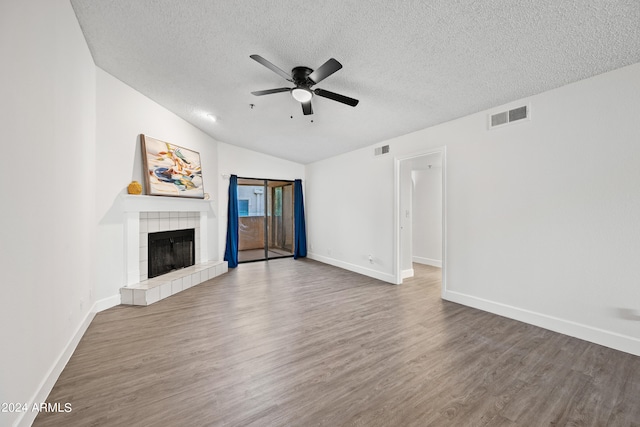 unfurnished living room featuring a tile fireplace, wood-type flooring, a textured ceiling, and vaulted ceiling