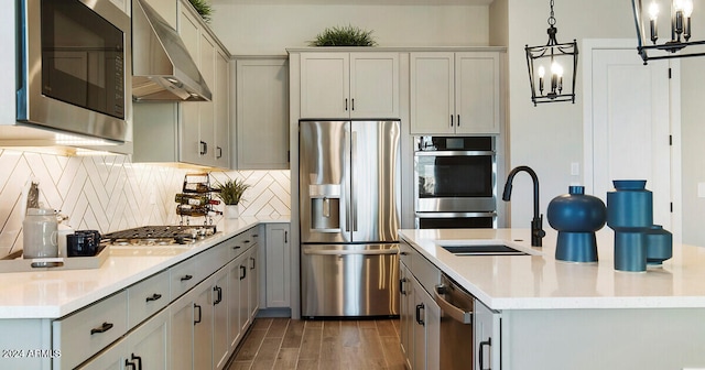 kitchen featuring hanging light fixtures, gray cabinets, stainless steel appliances, ventilation hood, and wood-type flooring