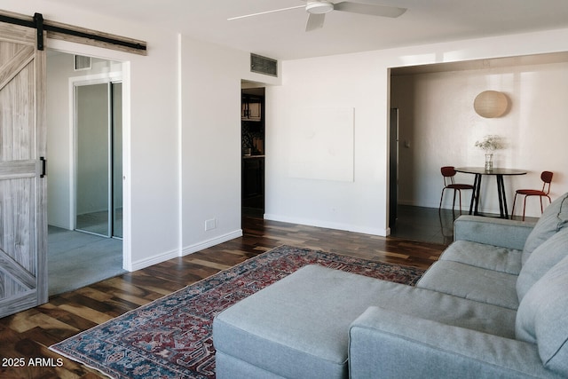 living room featuring a barn door, ceiling fan, and dark hardwood / wood-style floors