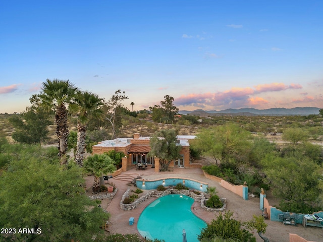 pool at dusk with a patio and a mountain view