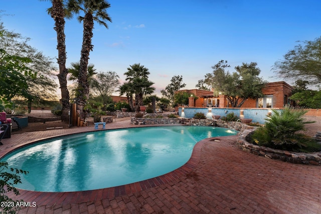 pool at dusk featuring a patio