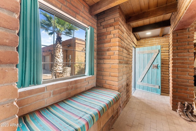 bedroom featuring multiple windows, brick wall, and beam ceiling