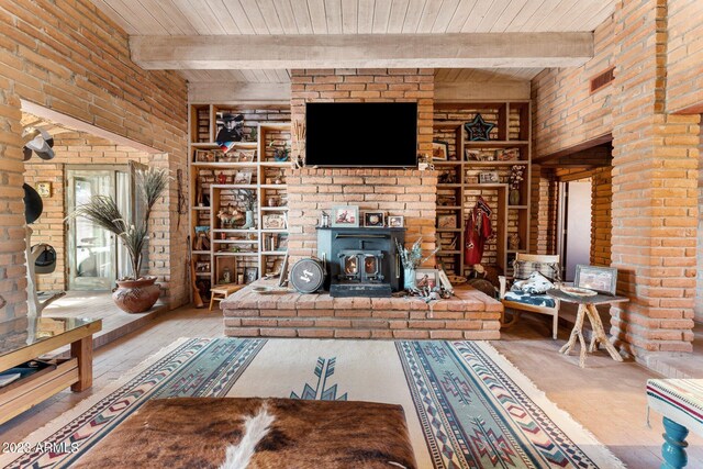 unfurnished living room with wooden ceiling, beamed ceiling, a brick fireplace, and a wood stove