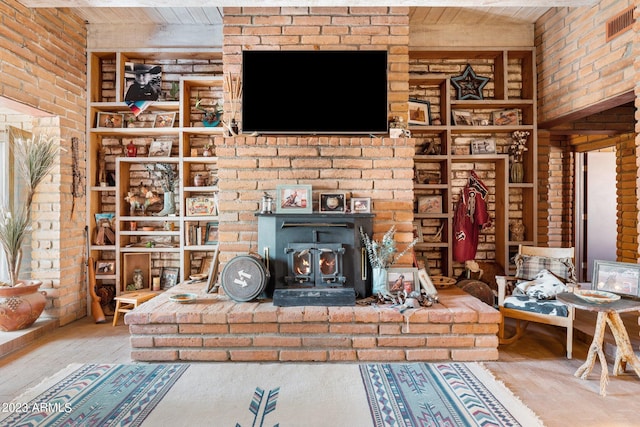 unfurnished living room featuring hardwood / wood-style flooring, a brick fireplace, wood ceiling, a wood stove, and brick wall