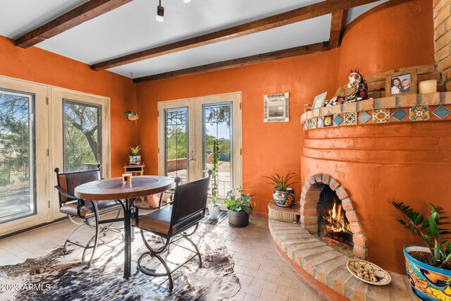 dining area with a fireplace, french doors, and beamed ceiling