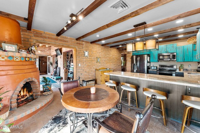 dining area featuring brick wall, sink, a brick fireplace, and beam ceiling