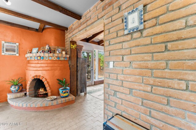 living room featuring beam ceiling and a brick fireplace