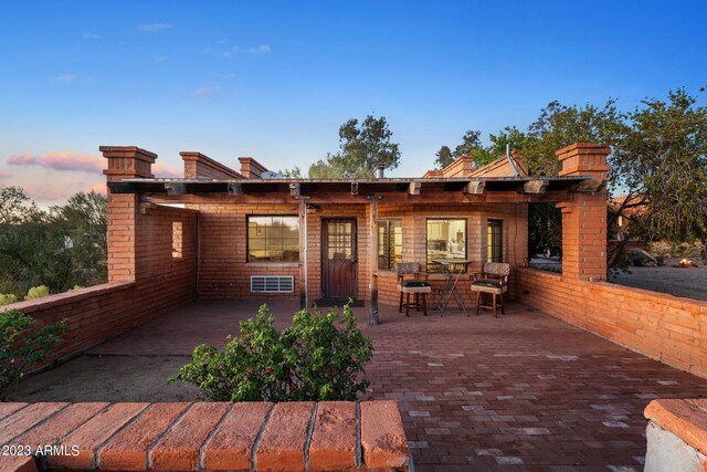 back house at dusk with a patio area