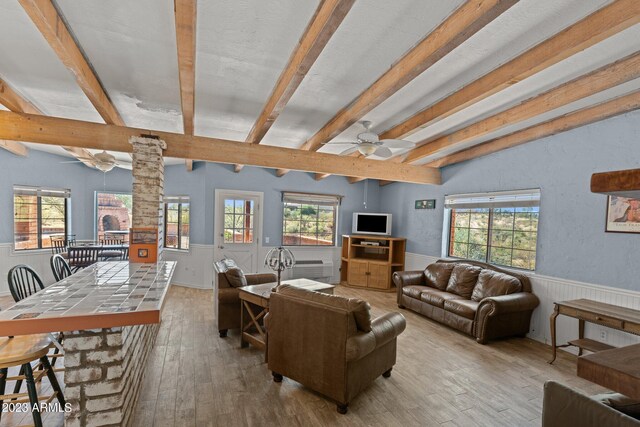 living room featuring light wood-type flooring, a wealth of natural light, beam ceiling, and ceiling fan